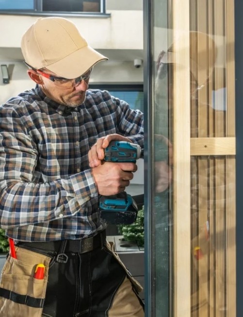 Técnico de DUVINOX realizando la instalación de un cerramiento de cristal con estructura metálica, utilizando herramientas especializadas y equipo de seguridad, garantizando un acabado funcional, estético y duradero.