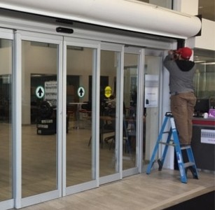 Instalación de puertas automáticas correderas de cristal en espacio comercial realizada por el equipo DUVINOX