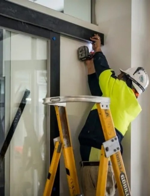 Técnico de DUVINOX realizando la instalación de un cerramiento de cristal con estructura metálica, utilizando herramientas especializadas y equipo de seguridad, garantizando un acabado funcional, estético y duradero.